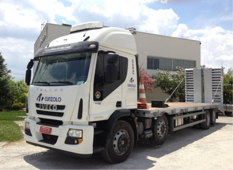 Caminhão Plataforma Carrega Tudo - Transporte Pesado e Remoções Industriais Este caminhão para transporte de cargas pesadas tem uma capacidade útil de 8,90 metros de comprimento e carrega um máximo de 15 toneladas, além de possuir rampa de acesso traseiro em aço com acionamento hidráulico.