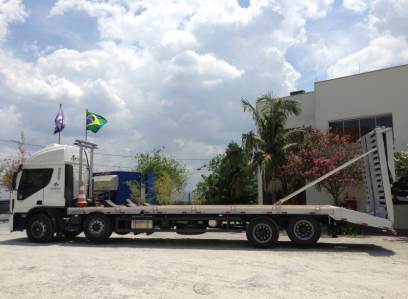 Caminhão Plataforma Carrega Tudo - Transporte Pesado e Remoções Industriais Este caminhão para transporte de cargas pesadas tem uma capacidade útil de 8,90 metros de comprimento e carrega um máximo de 15 toneladas, além de possuir rampa de acesso traseiro em aço com acionamento hidráulico.
